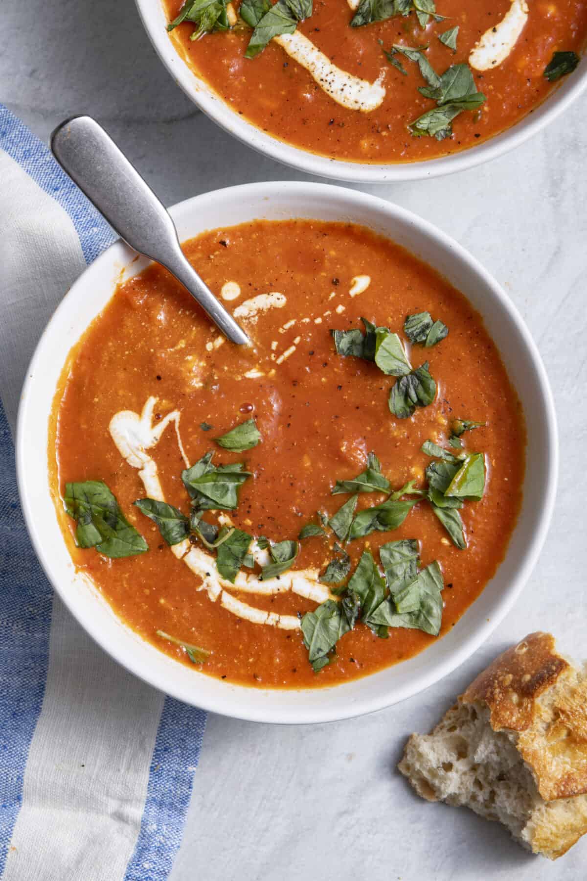 Roasted red pepper soup bowl with baguette next to it